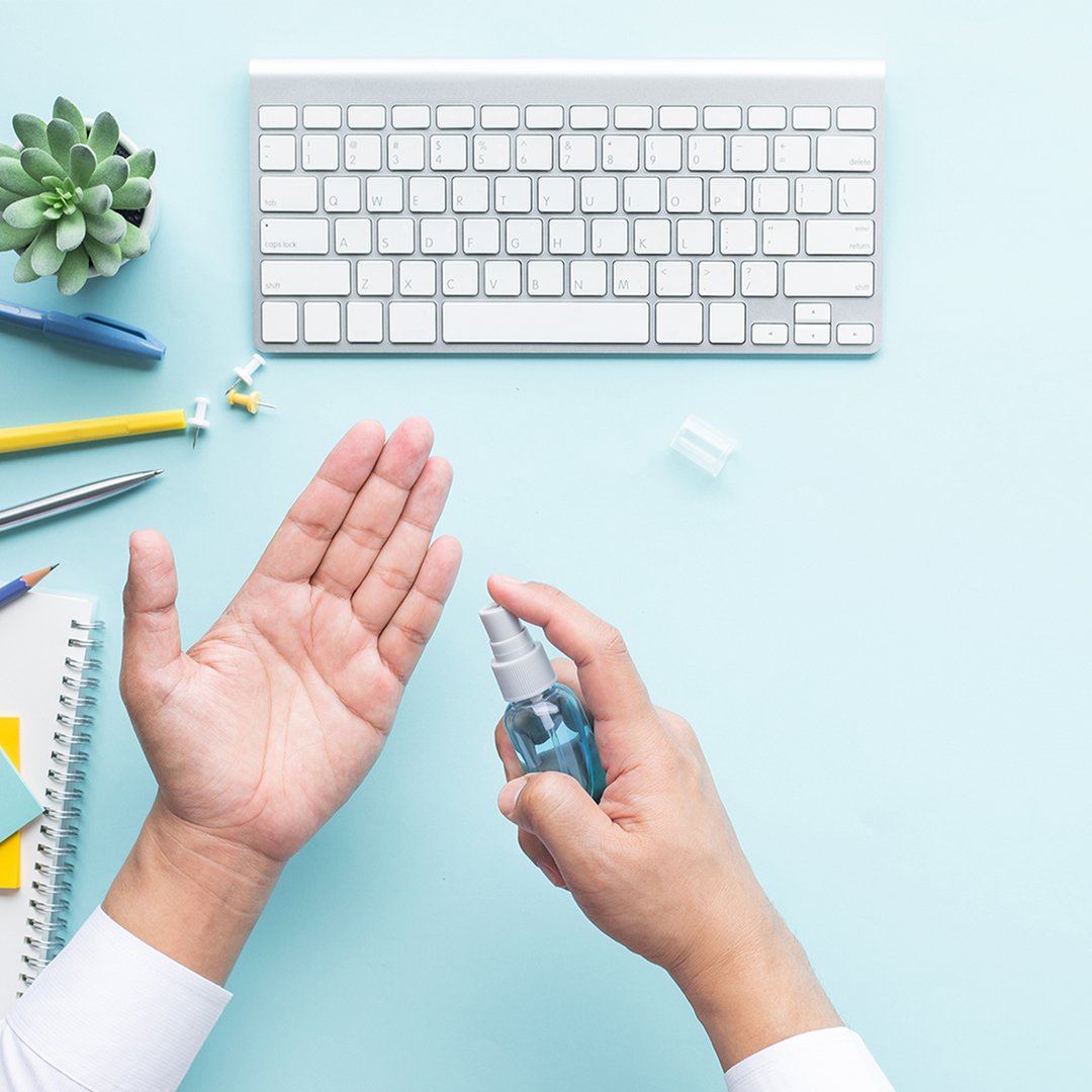 Personne appliquant un désinfectant pour les mains à son bureau à côté d'un clavier